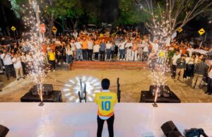 La seguridad según Carlos Caicedo: la propuesta que quiere romper la campaña Carlos Caicedo en meeting político, de espaldas a la cámara, con camiseta que dice CAICEDO