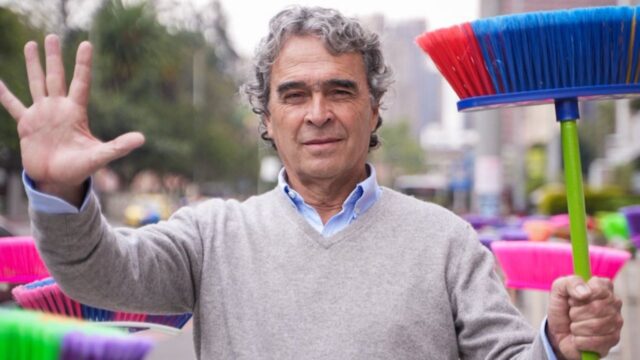 Fajardo sosteniendo una escoba y levantando la mano en numero 5.